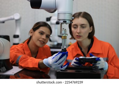Female engineers checking or maintenance electronic in AI Robot, robot arm in the manufacturing automation and robotics manufacture room.