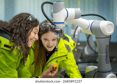 Female Engineers Collaborating on a Robot Control Project Learning and Technology: Women Engineers with Concentration on a Robotic Arm Two Female Workers Engaged in a Focused Learning Robotic Session.