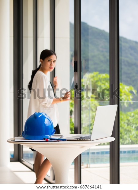 Female\
engineers standing at windows Engineer hats, laptops and a tool\
used in the design in construction\
concept
