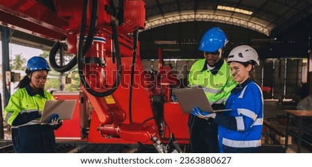 Female engineers work as a team training together in a modern technology world advanced robot welding machine factory.