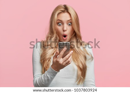 Female enterpreneur or businesswoman being disappointed with news from colleague, reads message on smartphone, shocked to recieve responsibility prepare difficult project for tomorrow`s meeting
