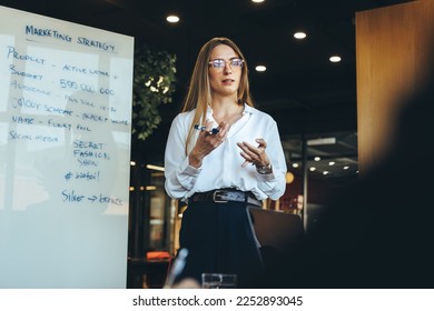 Female entrepreneur discussing her marketing strategy with her team in a modern workspace. Confident young businesswoman giving a presentation during a meeting with her colleagues. - Shutterstock ID 2252893045