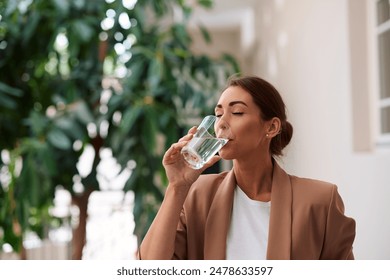 Female entrepreneur enjoying in a glass of fresh water while working int he office. Copy space. - Powered by Shutterstock