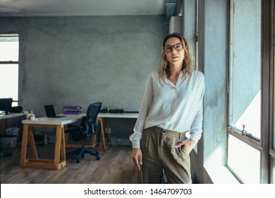 Female entrepreneur in her office. Woman in casuals standing by window and staring at the camera. - Shutterstock ID 1464709703