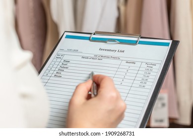 Female entrepreneur holding a clipboard with inventory list while doing inventory in her trendy clothing shop  - Powered by Shutterstock