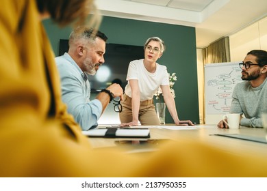Female entrepreneur leading a discussion with her business colleagues in a boardroom. Group of creative businesspeople sharing ideas during a meeting in a modern workplace. - Shutterstock ID 2137950355