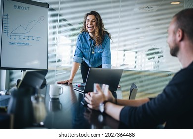 Female entrepreneur smiling while delivering a presentation to team in office boardroom. Businesswoman having meeting with colleagues with coworkers in office.