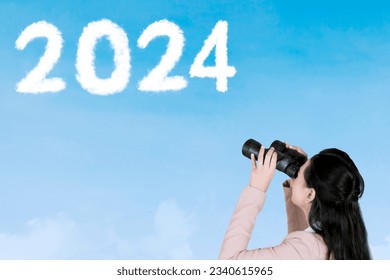 Female entrepreneur using binoculars while looking at clouds shaped 2024 numbers and upward arrow in the sky