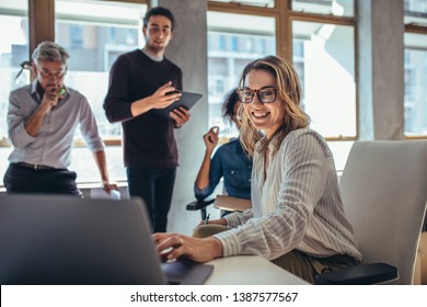 Female entrepreneur working on laptop and explaining strategy to attract followers to online web store while having meeting with colleagues in office. - Shutterstock ID 1387577567