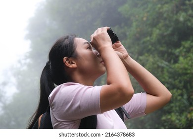 Female Environmentalist Using Binoculars In The Rainforest. Woman Explorer Use Binoculars To Travel And Have A Happy Smile. Tourists Looking Through Binoculars To See Wild Birds In The Jungle.