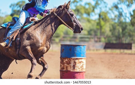 Female equestrian competing in barrel racing in dusty arena at outback country rodeo