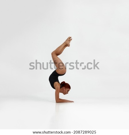 Female european ballet dancer dancing classical ballet dance. Choreography concept. Pretty flexible woman with red hair barefoot and wearing leotard. Isolated on white background in studio. Copy space