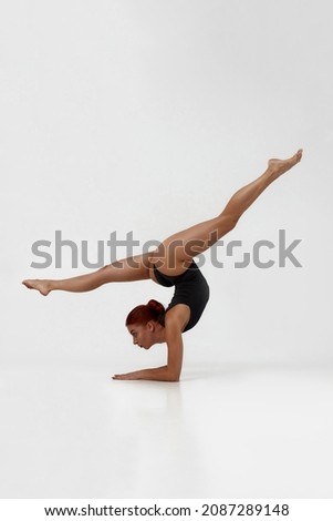 Female european ballet dancer dancing classical ballet dance. Choreography concept. Beautiful flexible girl with red hair barefoot and wear leotard. Isolated on white background in studio. Copy space