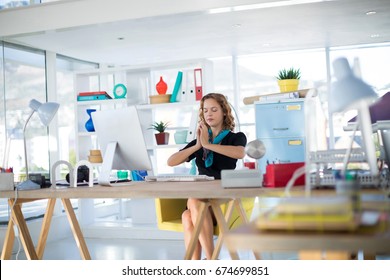 Female Executive Doing Yoga At Desk In Office