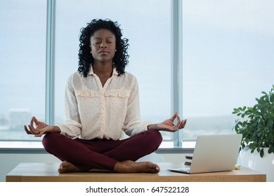 Female executive meditating on desk in office - Shutterstock ID 647522128