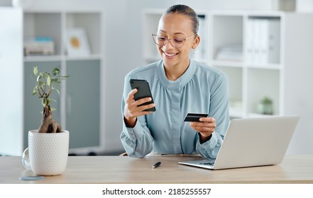 Female executive online shopping, buying with a corporate credit card on a phone. A smiling woman paying business bills, sitting at office desk with laptop. Happy lady making a purchase on a website - Powered by Shutterstock