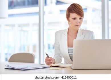 Female Executive Reading On Her Laptop While Working