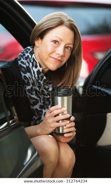 Female executive sitting\
in door of car