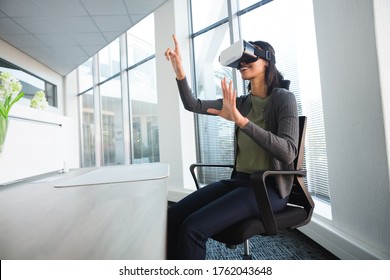 Female executive using virtual reality headset at desk in office - Powered by Shutterstock