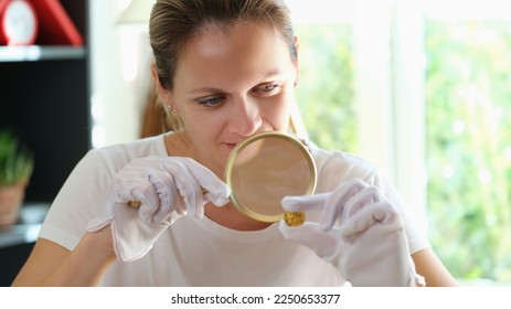 Female expert checks gold coin with magnifying glass. Estimating the value of antiques concept. - Powered by Shutterstock