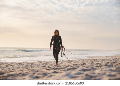 Female Extreme Sports Kite Surfer Prepping Kite On Beach During Sunset