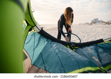 Female Extreme Sports Kite Surfer Prepping Kite On Beach During Sunset