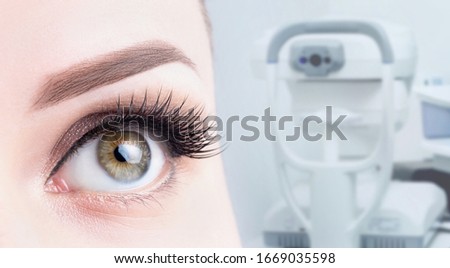 Female eye close-up on the background of ophthalmic equipment. Microscopy, vision diagnostics, treatment concept.