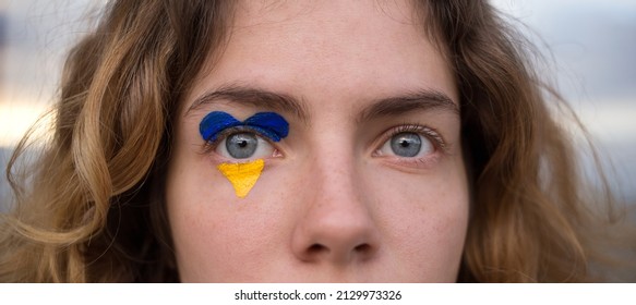 female eyes close-up with a drawn flag of Ukraine. National symbol of freedom and independence. Russian invasion of Ukraine, Stop the war. Hope and Faith