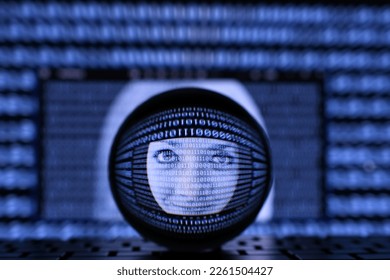 A female face in the midst of binary data stream on a computer screen as seen through a lens ball as a concept for AI artificial intelligence or operating system or identity theft online. 