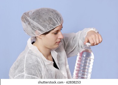 Female Factory Worker In The Bottling Industry Inspecting A Water Bottle