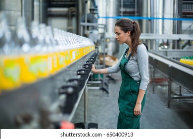 Female factory worker inspecting production line at drinks production factory