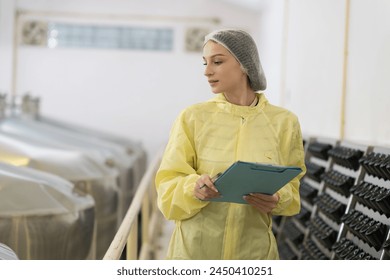 Female factory worker inspecting quality of wine bottles during manufacturing in process in fermentation wine factory. Wine manufacturing industry concept - Powered by Shutterstock