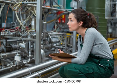 Female factory worker maintaining record on clipboard in drinks production factory - Powered by Shutterstock