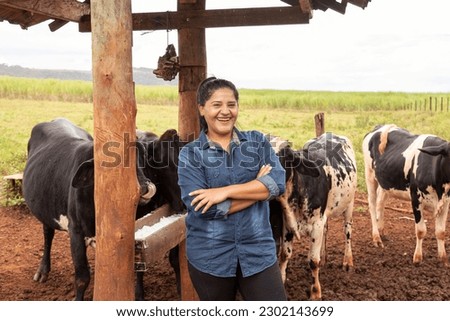 female farmer with arms crossed smiling looking at camera in meadow