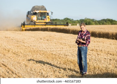 female farmer with combine harvester in wheat field