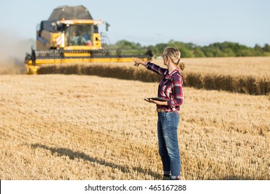 female farmer with combine harvester in wheat field