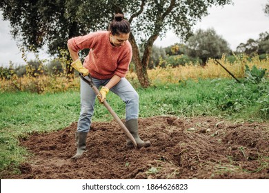 Female farmer digging ground in cloudy autumn day. Woman working with shovel in field - Powered by Shutterstock