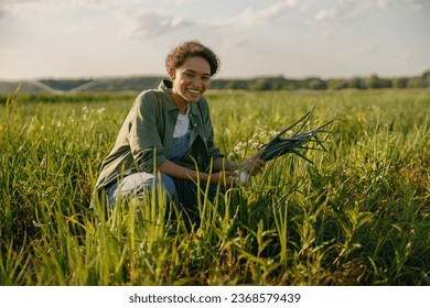 Female farmer holding bunch of onion on field during harvesting. Agricultural occupation concept - Shutterstock ID 2368579439