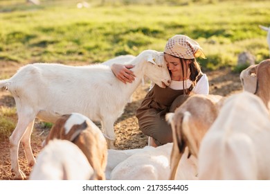 Female Farmer Taking Care Of Cute Goats. Young Woman Getting Pet Therapy At Ranch. Animal Husbandry For The Industrial Production Of Goat Milk Dairy Products. Agriculture Business And Cattle Farming.