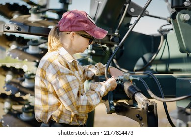 Female farmer trying to repair tractor in field. Fixing combine harvester. - Shutterstock ID 2177814473