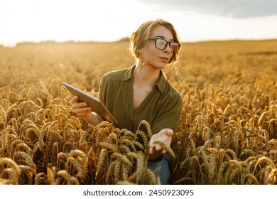 Female farmer using digital tablet in wheat field. Smart farming and digital agriculture. - Powered by Shutterstock