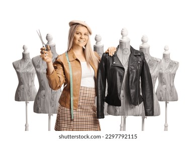 Female fashion designer leaning on a mannequin doll with a leather jacket and holding scissors isolated on white background