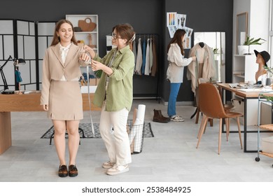 Female fashion designer taking measurements of client in studio - Powered by Shutterstock