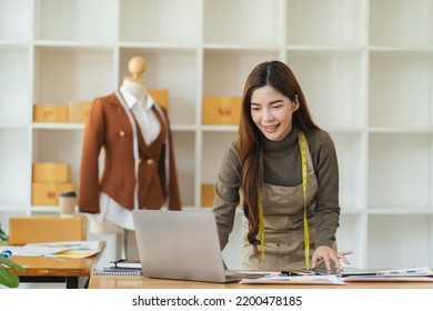 Female Fashion Designer Works On New Womenswear Collection For Clients In Cozy Workshop Studio, Dressmaker, Tailor Or Needlewoman Standing Near Clothing Rack With Fashionable Stylish Handmade Clothes