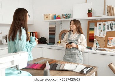 Female fashion designers with cups of coffee in studio - Powered by Shutterstock