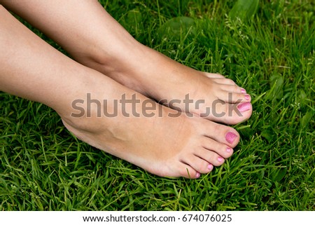 Female feet with a beautiful manicure on a background of green grass