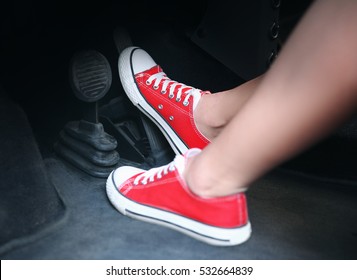 Female feet with brake and accelerator pedals