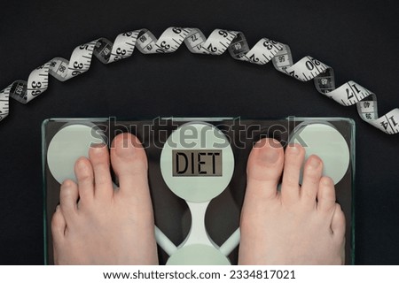 female  Feet on floor scales, body weight control, the word DIET on the dial of the scales