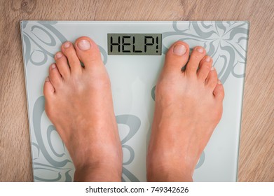 Female feet on personal scales with word HELP! - obesity and diet concept