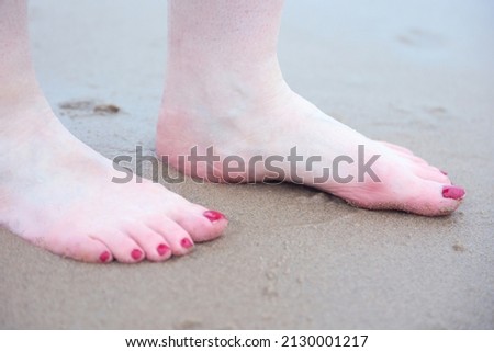 Female feet on a wet sandy beach close up